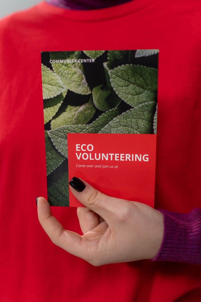Close-up of a volunteer holding an eco volunteering brochure with nature design.